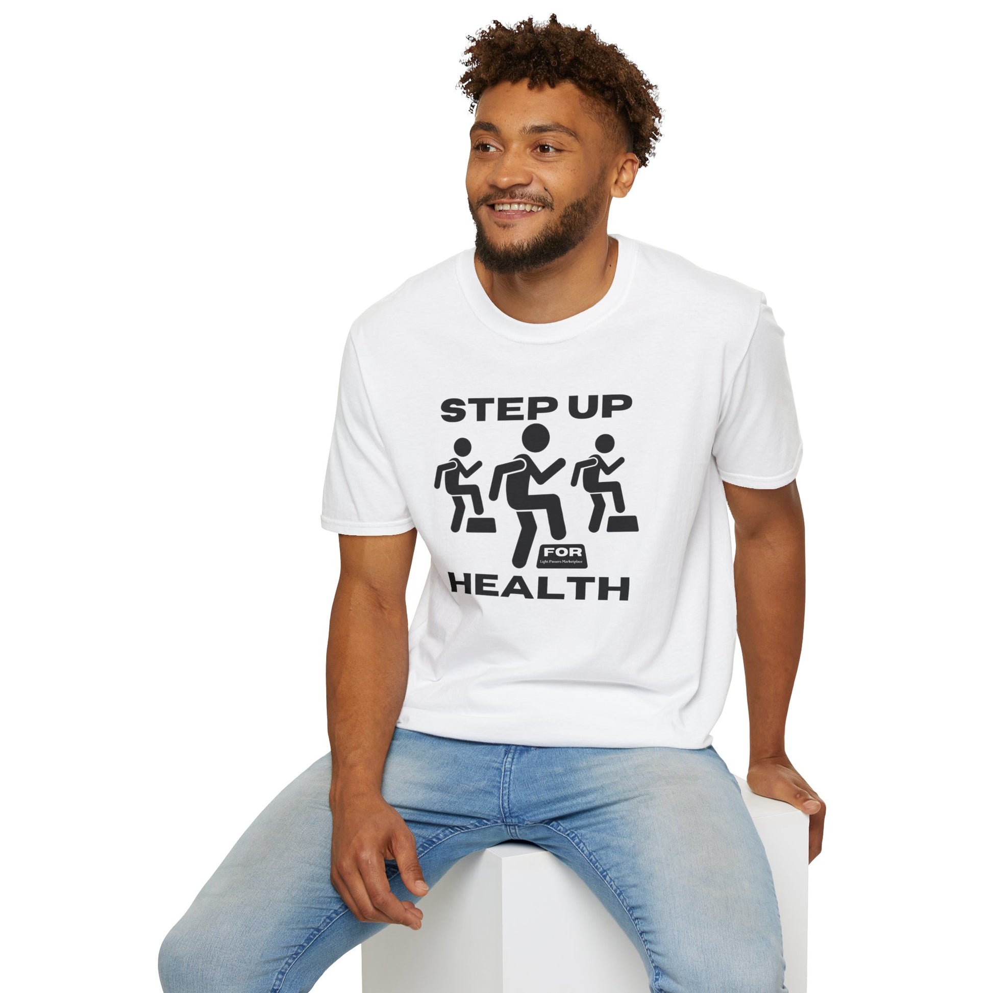 A man in a white Step Up For Health unisex t-shirt, sitting on a cube. The tee is 100% cotton, featuring twill tape shoulders for durability and a ribbed collar. Made with ethically grown US cotton.