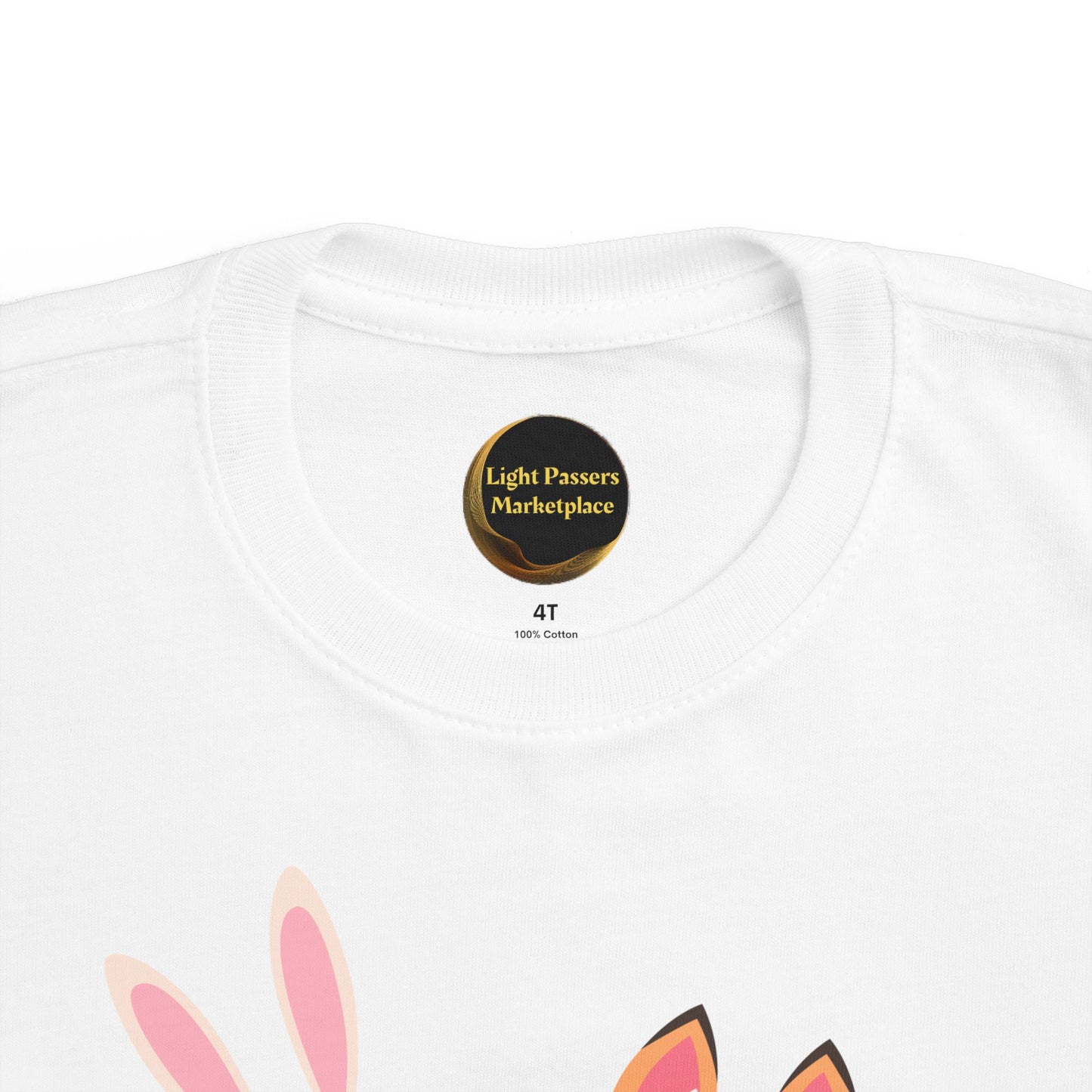 The Light Never Stop Reading Toddler Tee features a collar label from Light Passers Marketplace and animal ears graphic, combining comfort with storybook inspiration.