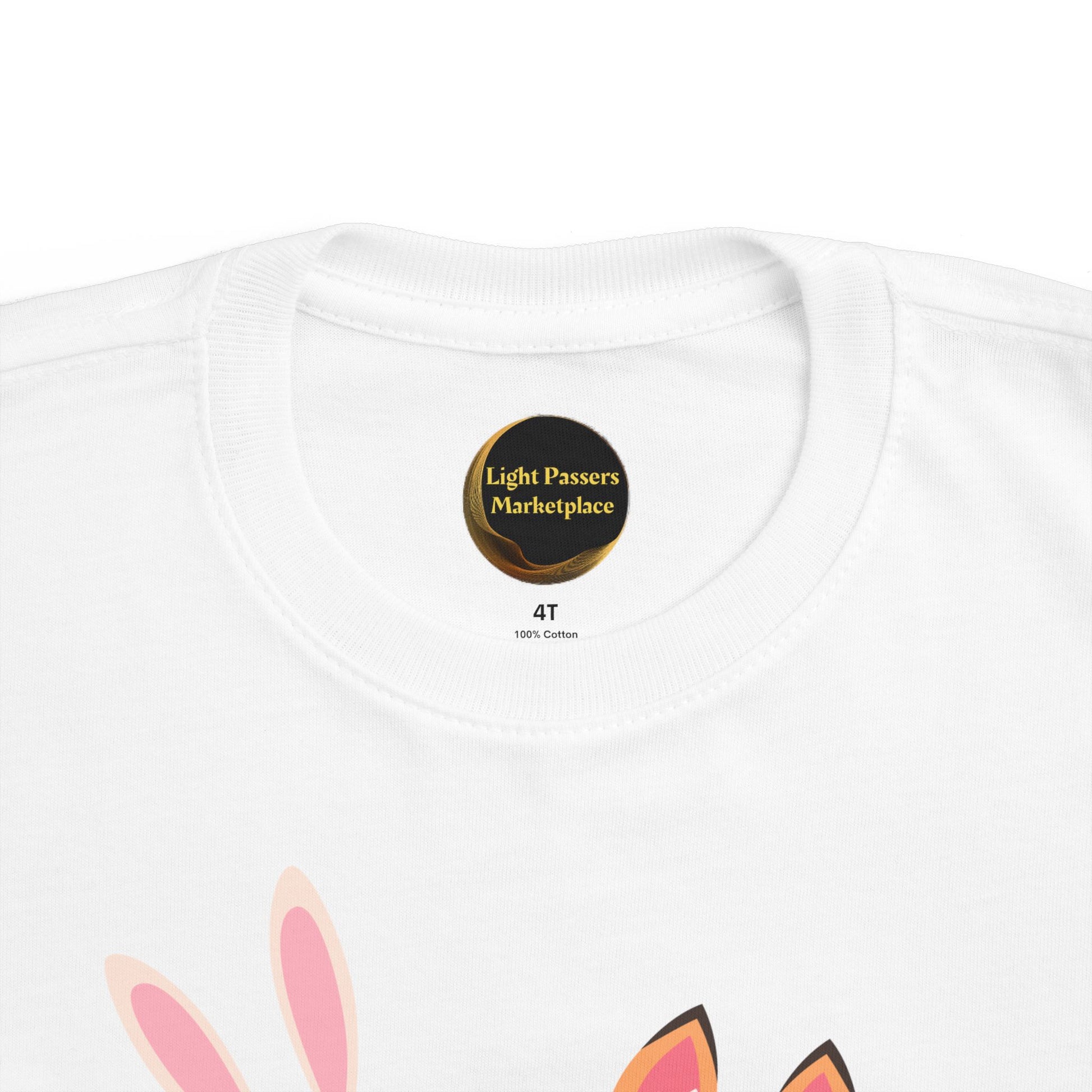 The Light Never Stop Reading Toddler Tee features a collar label from Light Passers Marketplace and animal ears graphic, combining comfort with storybook inspiration.