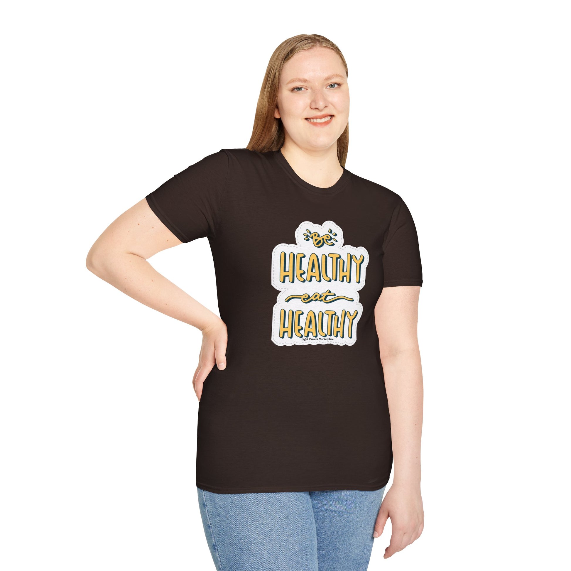 A woman in a black shirt smiles, posing for a picture. Close-up of blue jeans and a white and yellow sign. Be Healthy Eat Healthy Unisex T-Shirt features soft 100% cotton, twill tape shoulders, and ribbed collar.