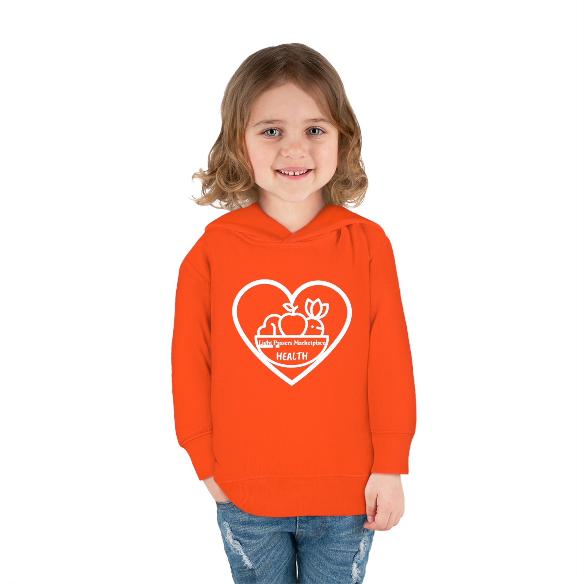 A smiling toddler in an orange Fruit Basket Toddler Hoodie with heart and fruit logo, featuring side-seam pockets and double-needle hem hood for durability and comfort.
