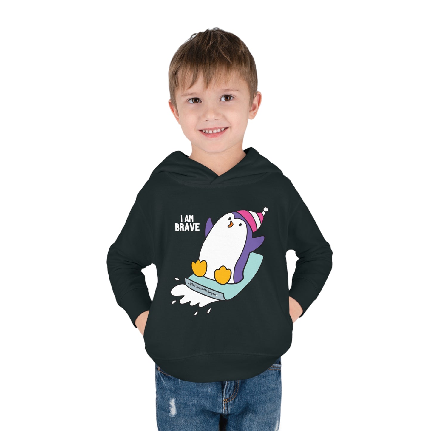 A smiling boy in a Brave Penguin Toddler Hooded Sweatshirt with penguin design. Features jersey-lined hood, side seam pockets, and durable stitching for lasting coziness.