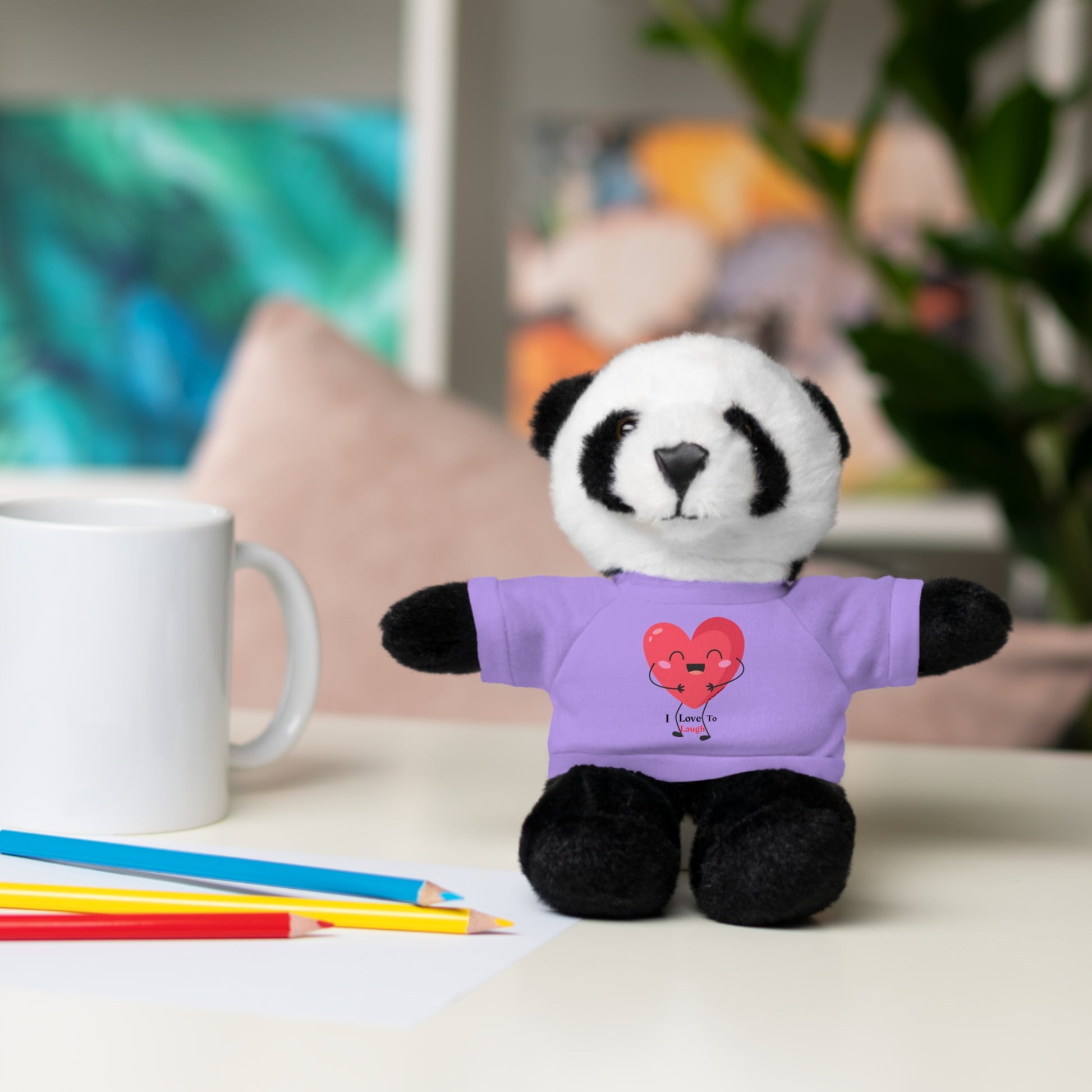 Stuffed panda bear with I Love to Laugh heart on removable purple T-shirt, part of Cool Stuff Stuffies collection, on display.