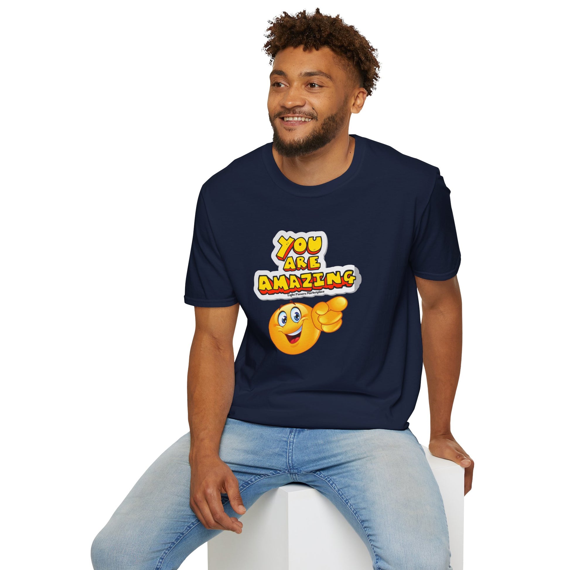 A man in a blue shirt sits on a white cube, a yellow smiley face points at the camera. Unisex soft-style tee, 100% cotton, no side seams, ribbed collar, ethically made, lightweight fabric.