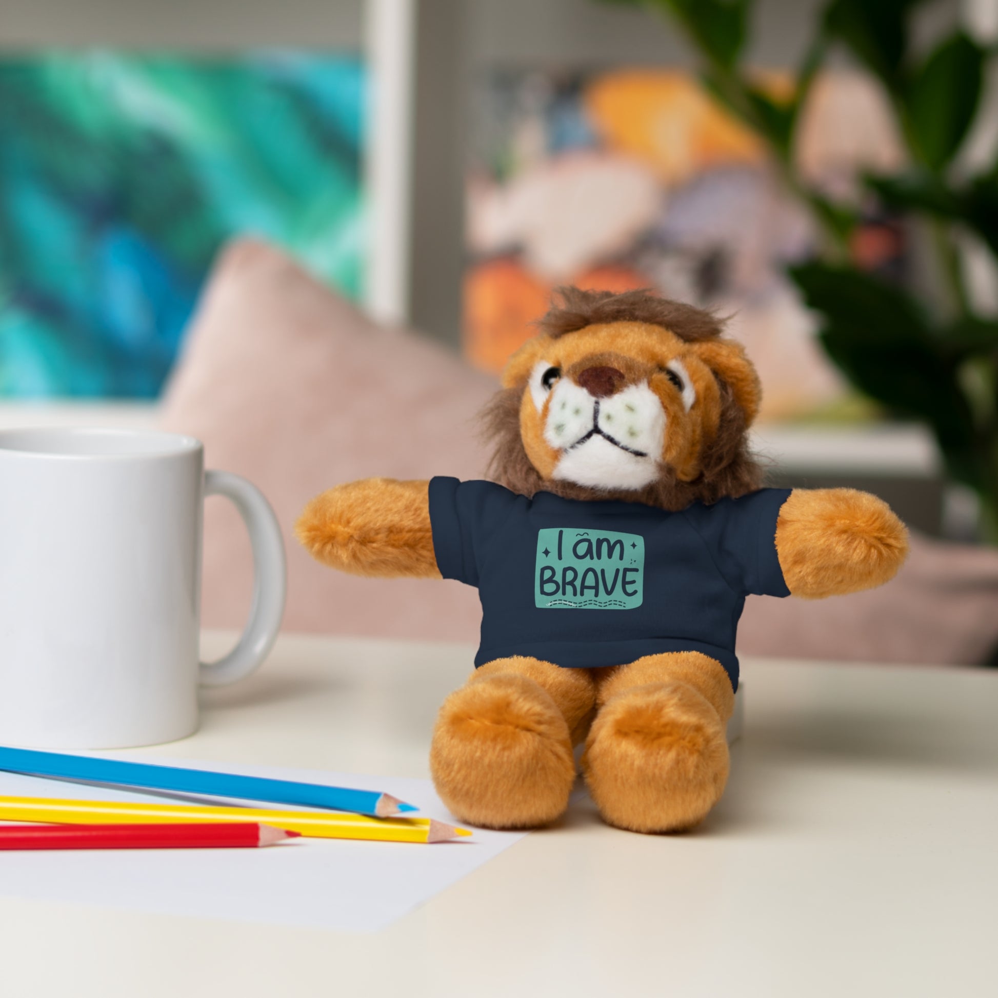 Stuffed lion toy Cool Stuff Stuffies with I am Brave shirt, sitting on a table, part of customizable plush animal collection.
