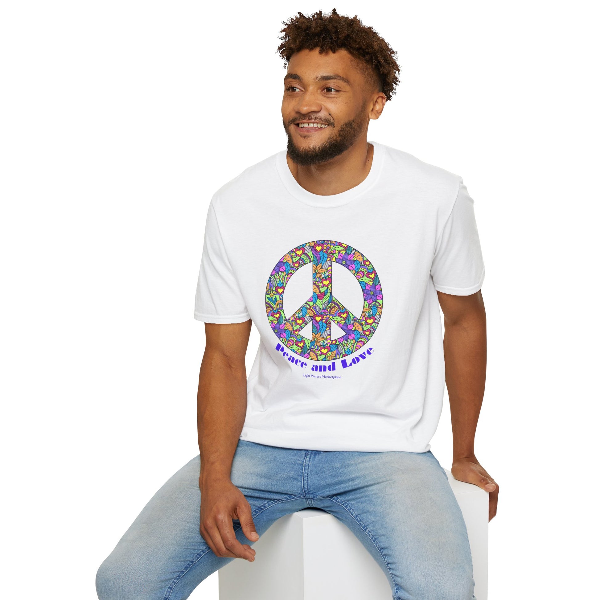 A man in a Peace sign with flowers Unisex T-shirt, sitting on a cube. Soft 100% cotton tee with twill tape shoulders, no side seams, and ribbed collar. Ethically made, lightweight fabric for year-round comfort.