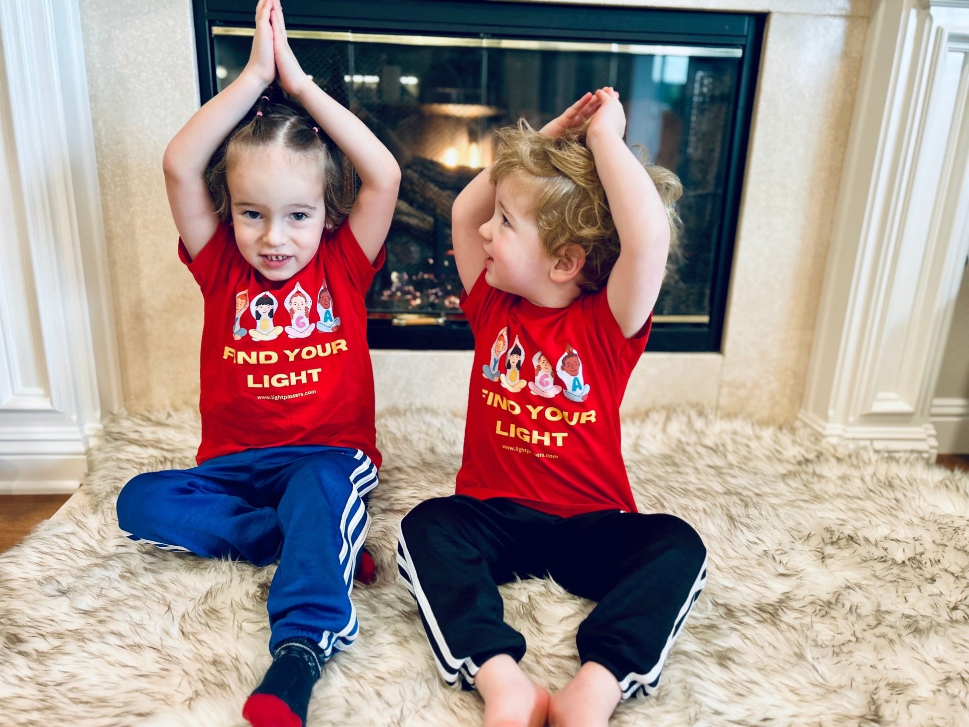 A toddler wearing a red shirt with cartoon girls on it, sitting on a fur rug. The tee is soft, durable, and made of 100% combed cotton for sensitive skin.