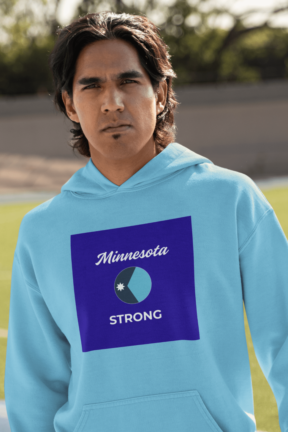 Young man on a sports field wears the Love and Peace The Light Minnesota Strong Hoodie, showcasing its Minnesota-inspired graphic and cozy, relaxed fit.