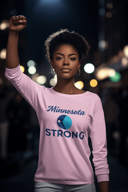 Young woman in urban setting wearing Love and Peace The Light Adult Unisex Minnesota Strong Long Sleeve Tee, raising a fist, embodying resilience and community pride.
