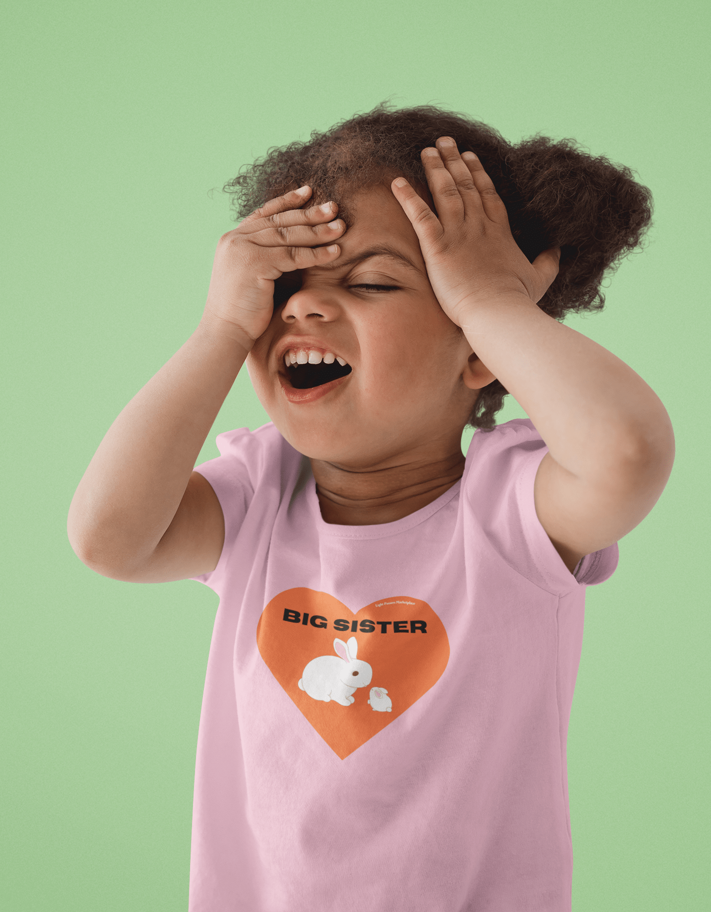 A toddler in a pink shirt with hands on face, embodying comfort and durability. Big Sister Toddler T-shirt in soft, 100% combed cotton, tear-away label, and classic fit.