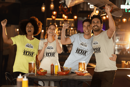 A diverse group of people in a restaurant, embodying confidence and joy, wearing the You are Amazing Group Unisex T-Shirt. Made of soft, durable 100% cotton with twill tape shoulders and ribbed collar.