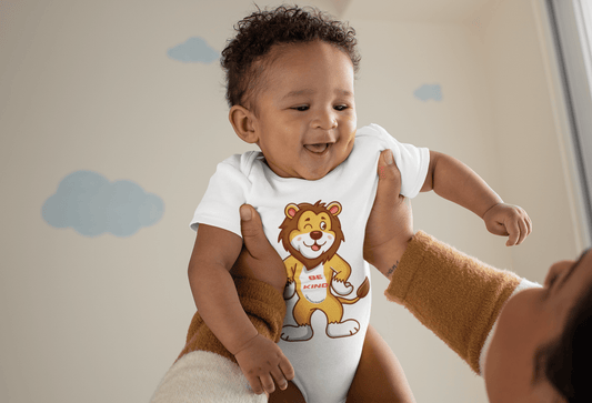 A baby wearing a lion shirt held by a person, showcasing a close-up of the lion design. Organic cotton Onesie® with snap closure, OEKO-TEX® certified for softness and breathability.