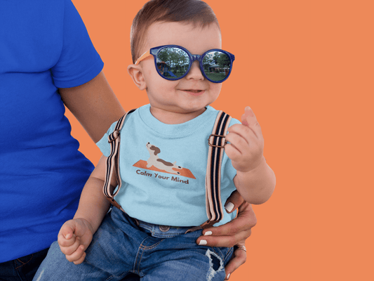 A baby wearing sunglasses and suspenders, a blue shirt, and a dog on fabric. Infant fine jersey tee with side seams, ribbed knitting, and taped shoulders for comfort and durability.