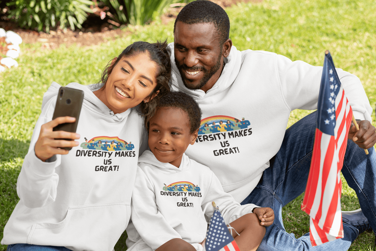 A diverse group of people sitting on grass, smiling and taking a selfie. Unisex heavy blend hooded sweatshirt made of cotton and polyester, featuring a kangaroo pocket and color-matched drawstring.