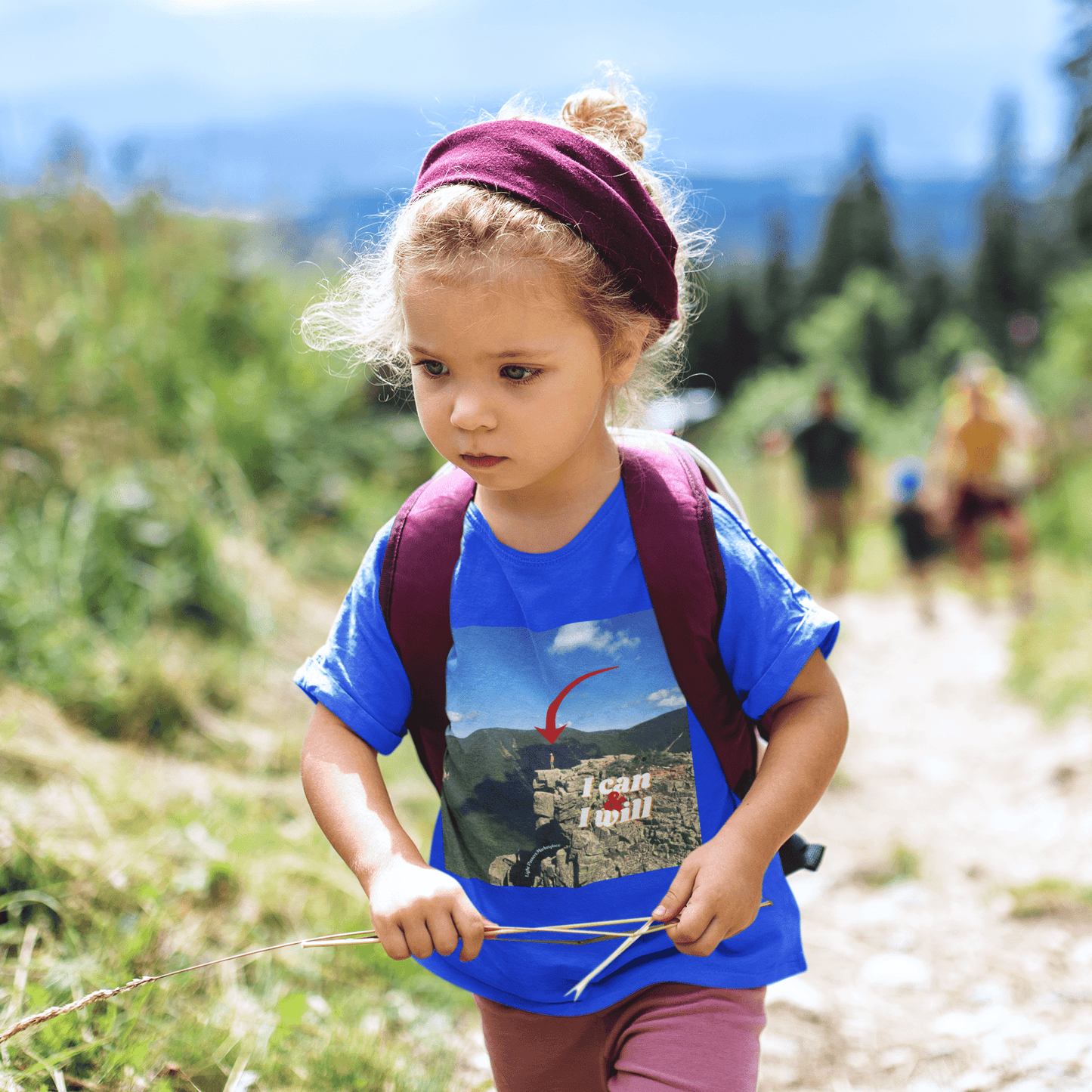 A toddler wearing a hiking-themed t-shirt with the text I Can and I Will. Made of 100% Airlume combed cotton, tear-away label for comfort. Ideal for outdoor adventures.