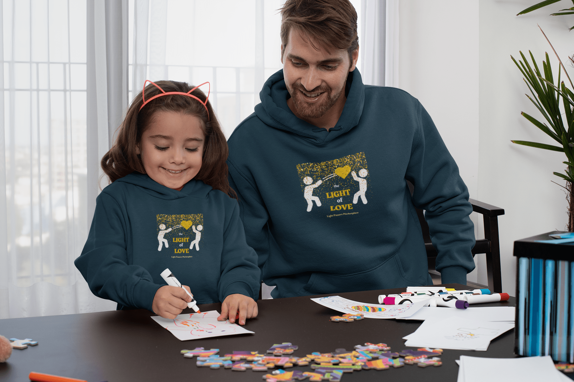 A toddler hoodie featuring a man and a girl drawing, a girl writing on a whiteboard, and a man wearing a sweatshirt. Designed for comfort with side-seam pockets and durable stitching.