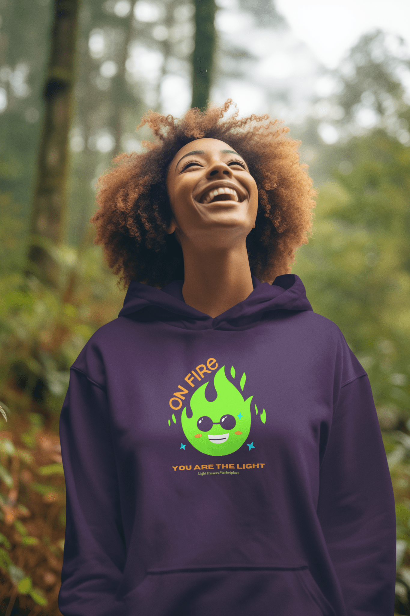 A woman in a purple sweatshirt with a cartoon smiles, showcasing the On Fire You are the Light Unisex Hooded Sweatshirt's cozy blend of cotton and polyester.