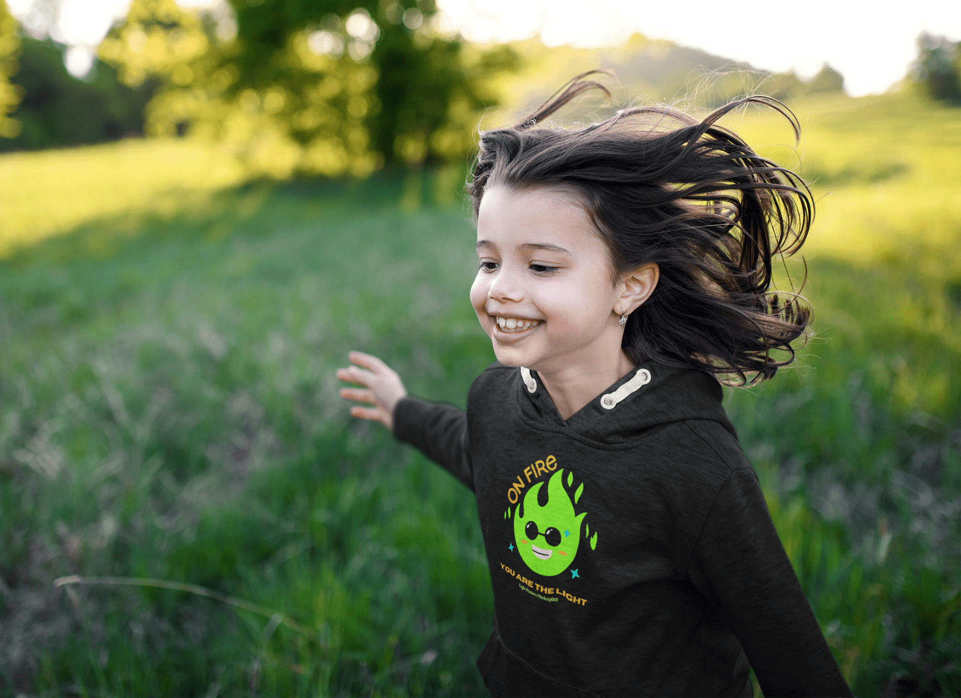 A toddler in a black hoodie with a green flame design, featuring a jersey-lined hood, cover-stitched details, and side seam pockets for cozy durability.