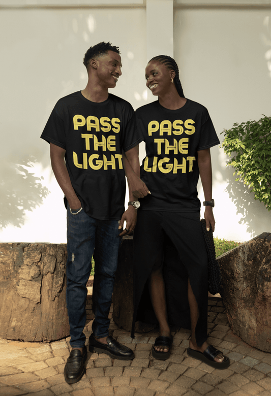 A man and woman in matching PASS THE LIGHT Unisex T-shirts. Black shirts with yellow text. Focus on the design and fit of the classic, 100% cotton tee.