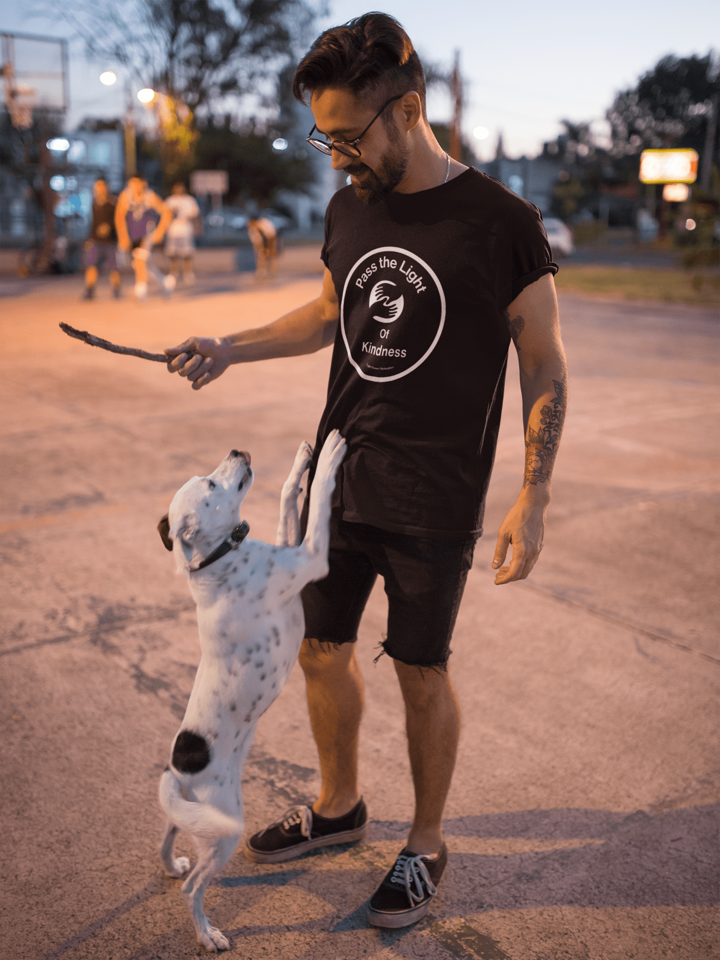 A man with a dog, wearing a black shirt, plays outdoors. Pass the Light of Kindness 2 hands Unisex T-shirt, 100% cotton, no side seams, tear-away label, classic fit.