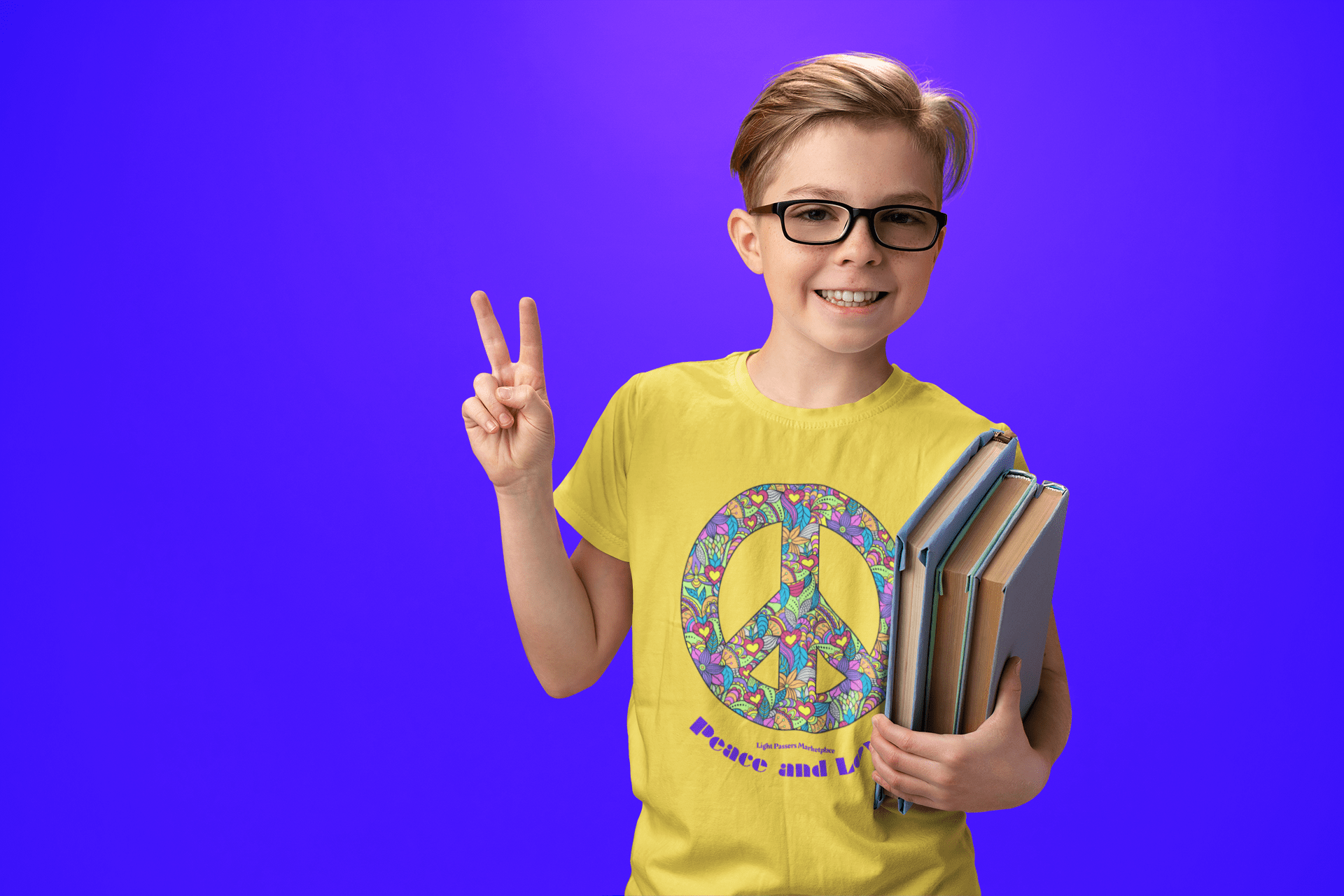 A boy in glasses smiles, holding books and a peace sign on a blue background. Youth heavy cotton t-shirt with 100% cotton fabric, ribbed collar, and tear-away labels.