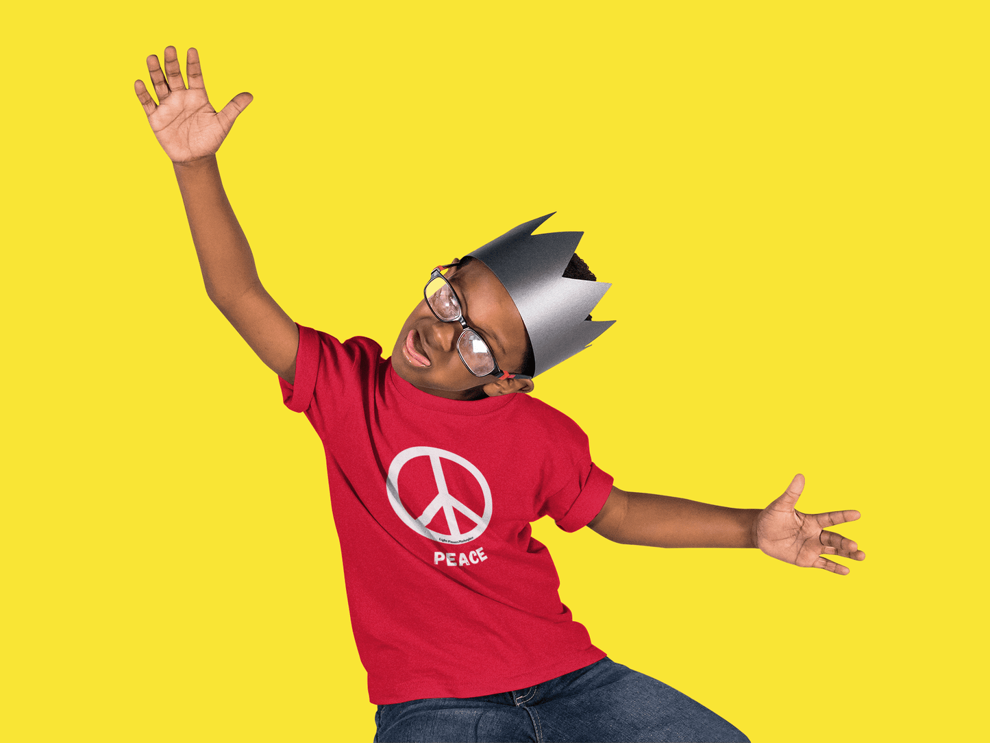 A boy in a paper crown and glasses, showcasing a Peace Sign white or black Youth T-shirt. Made of 100% US cotton, with twill tape shoulders and ribbed collar for durability and comfort.