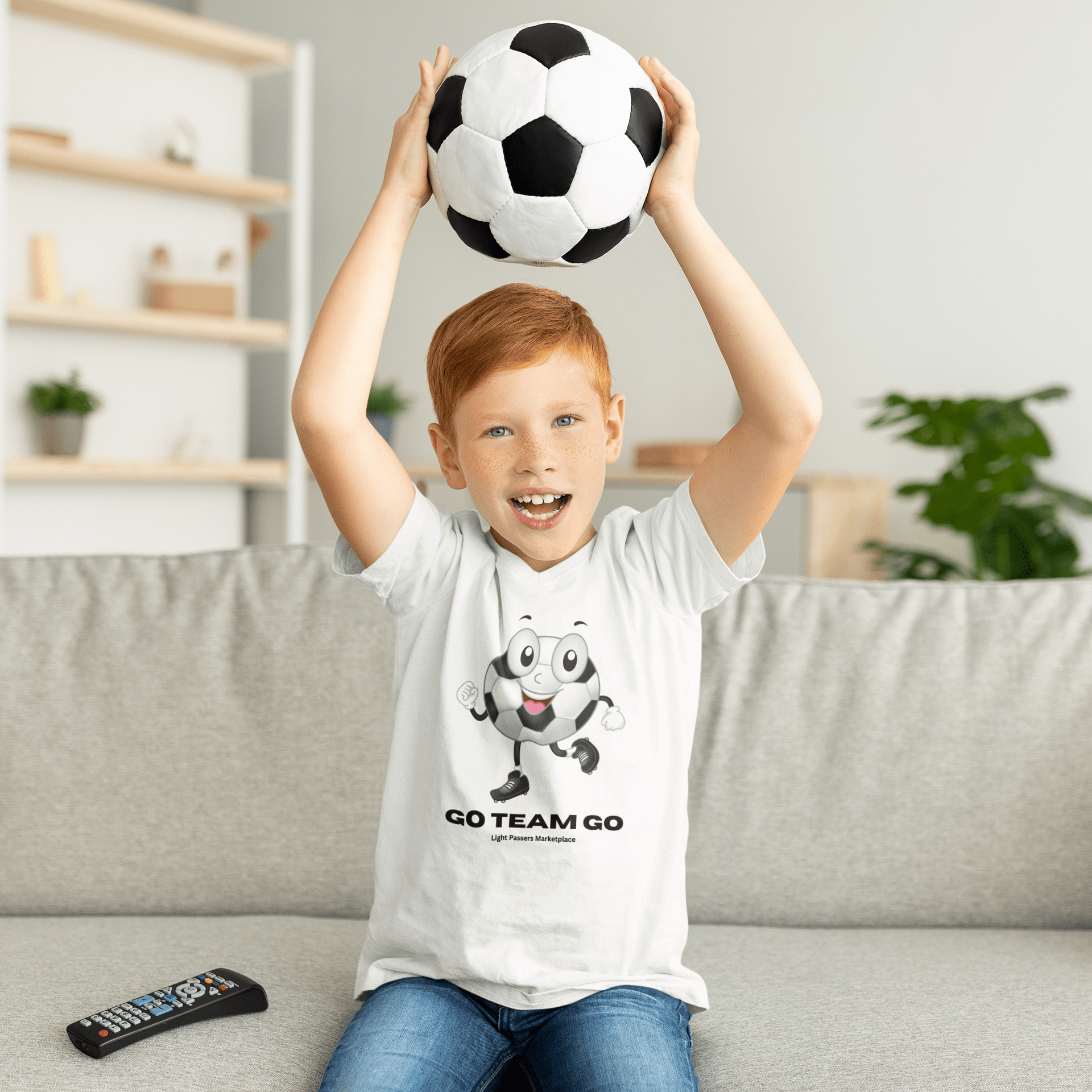 A youth t-shirt featuring a boy holding a soccer ball, made of 100% cotton with twill tape shoulders for durability. Classic fit with tear-away labels for comfort. Ethically sourced US cotton.