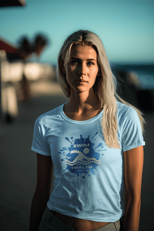 A woman with long blonde hair wearing a white Swim for Health unisex t-shirt on a beach. Soft 100% cotton tee with twill tape shoulders, ribbed collar, and tear-away label. Ethically made.