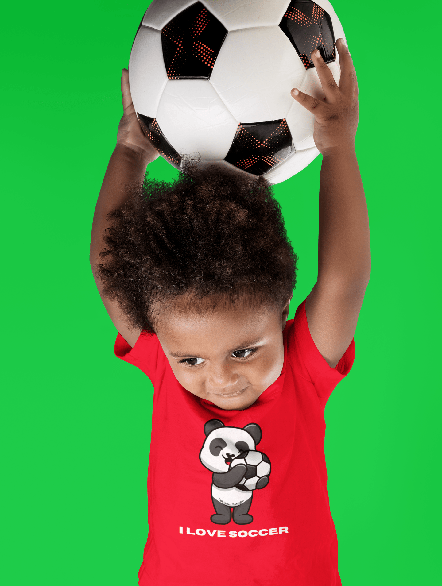 A toddler holding a soccer ball, wearing a soft tee with a durable print. Made of 100% combed cotton, light fabric, tear-away label, classic fit, true to size.