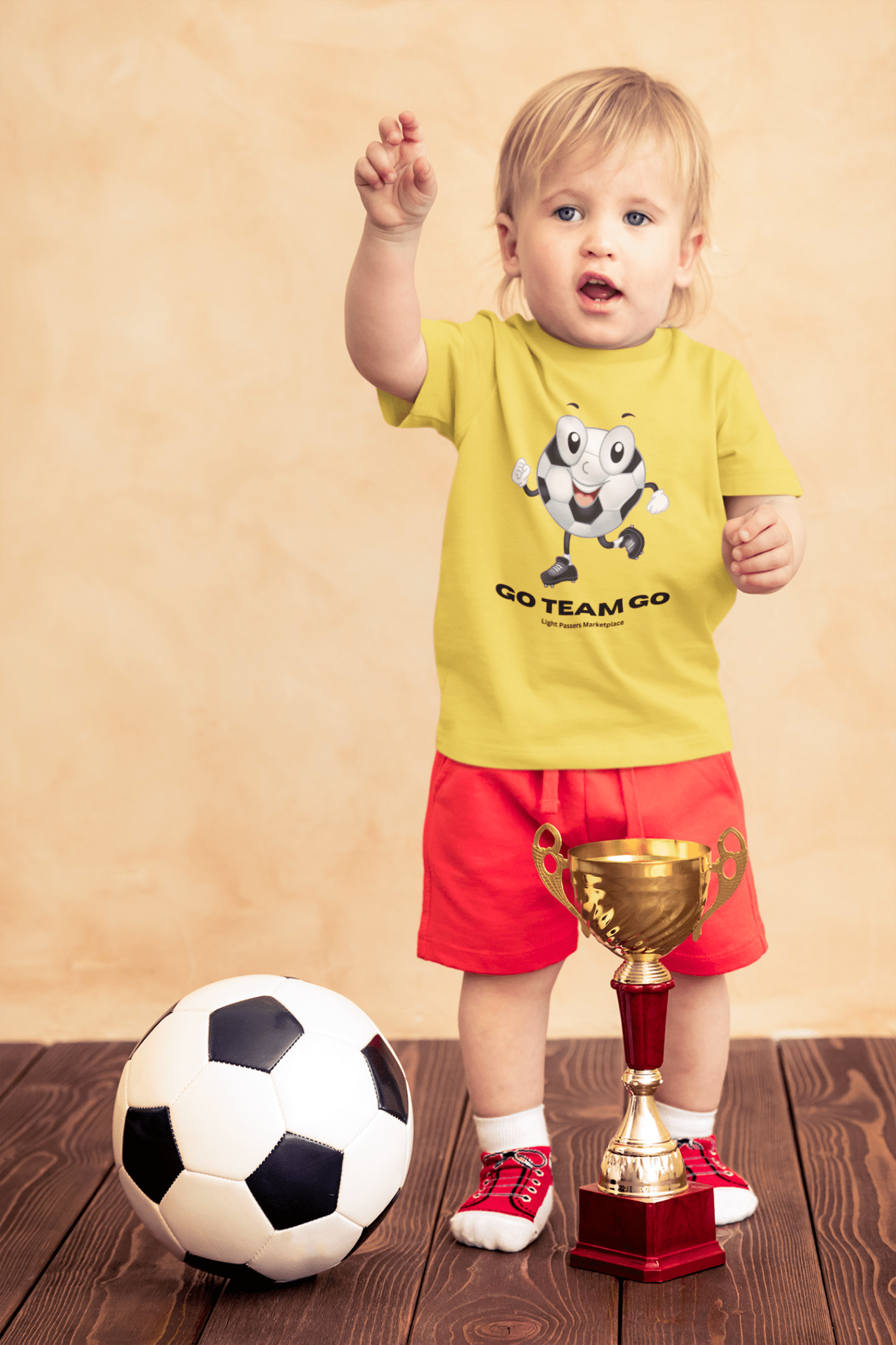 A toddler proudly holds a trophy, surrounded by a football ball and a close-up of a trophy. The image features a child wearing a yellow shirt and a sock. The focus is on sports and achievement.