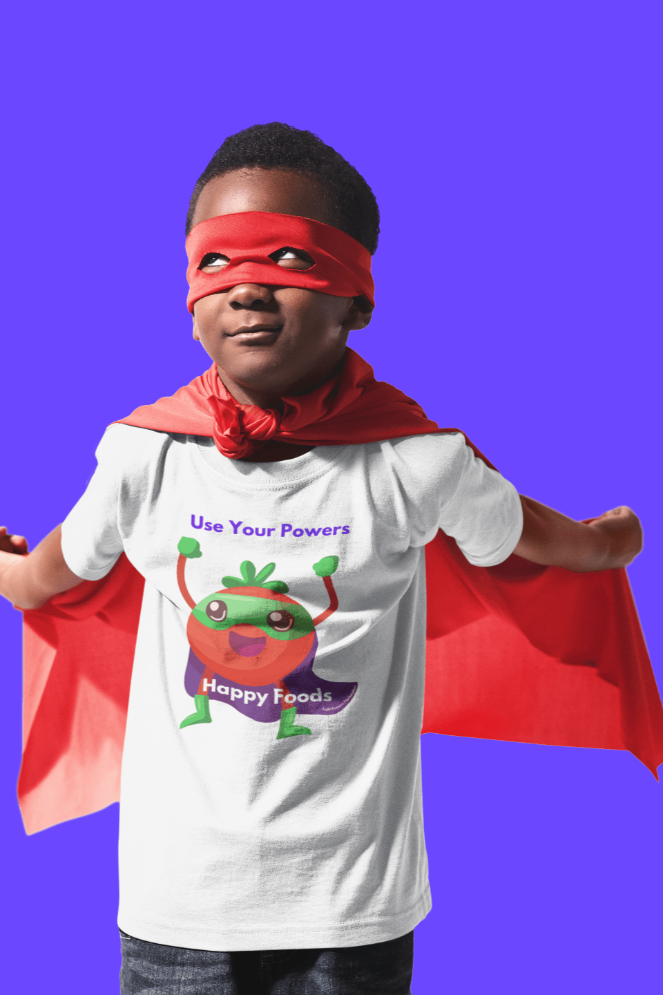 A toddler wearing a Tomato Power Toddler T-shirt with a red cape, featuring a durable print on soft cotton fabric, perfect for sensitive skin.