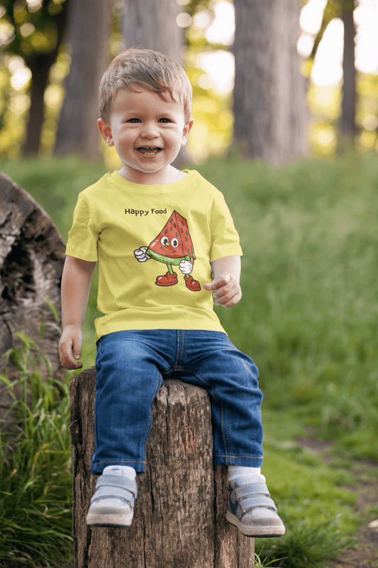 A toddler in a yellow shirt sits on a tree stump, smiling. Happy Food Watermelon Toddler T-shirt made of soft, durable cotton, perfect for sensitive skin.