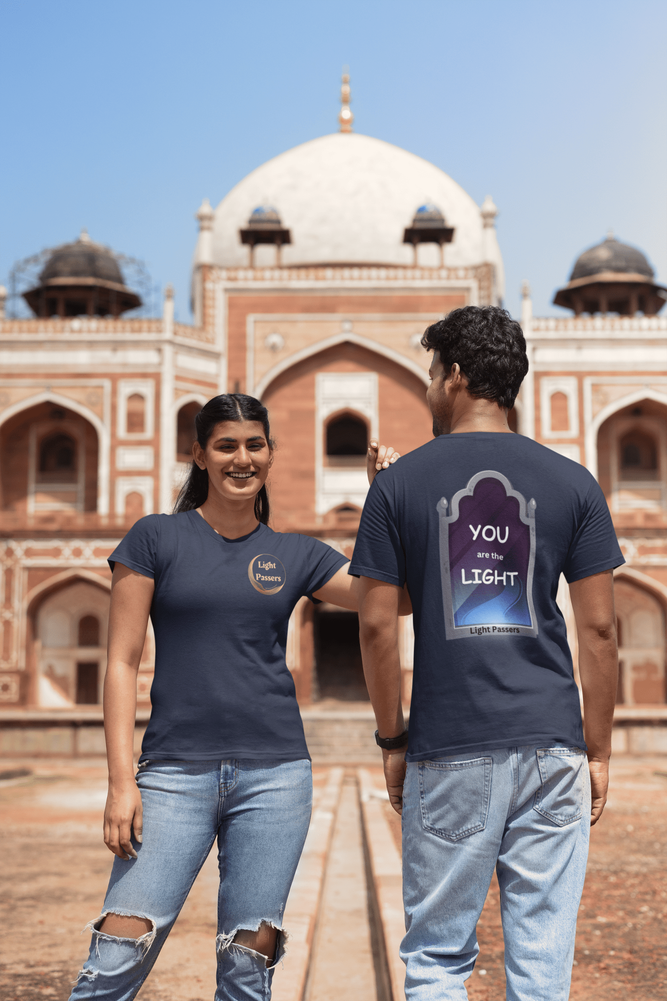 A man and woman in front of a building wear the Light Mirror BACK LP Logo FRONT Unisex T-shirt. Classic fit, 100% cotton tee with no side seams for comfort and durability.