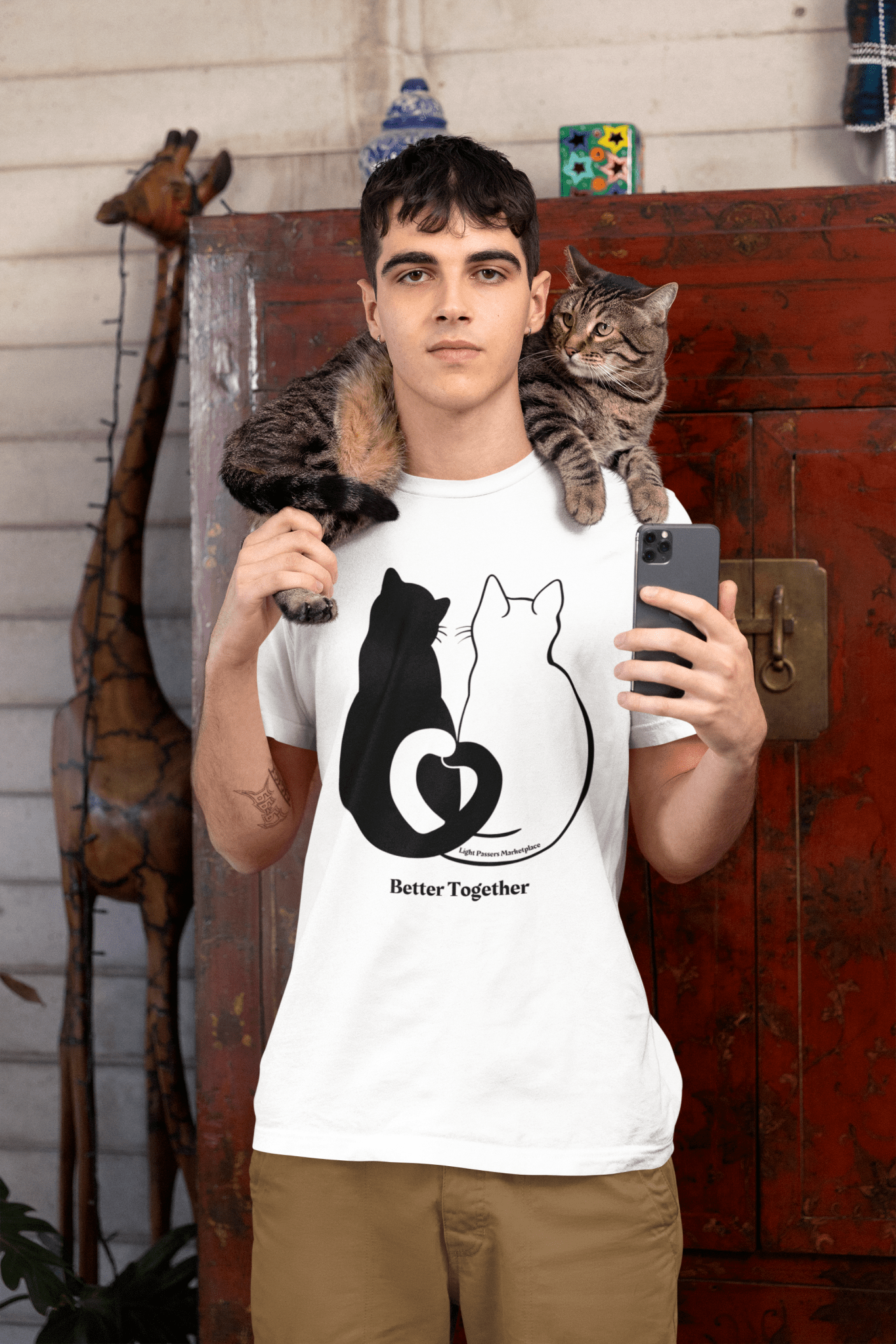 Man wearing Love and Peace Cat Love Adult Unisex T-Shirt with a black and white cat on his shoulder, holding a phone for a selfie.
