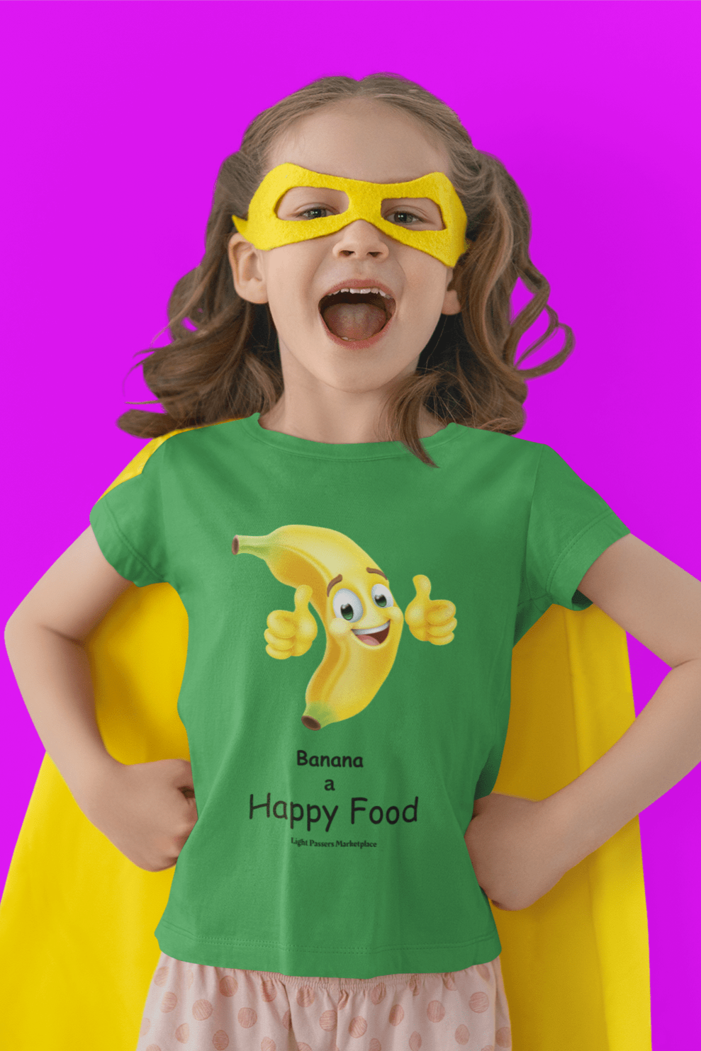 A girl in a Banana Happy Food Youth T-shirt, smiling, wearing a yellow mask. 100% cotton tee with twill tape shoulders, ribbed collar, and tear-away labels for comfort. Ethically made with US cotton.