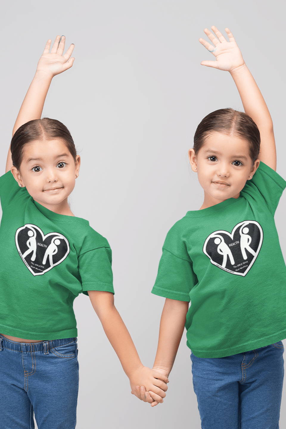 Two girls in green shirts holding hands, posing for the camera on a kids heavy cotton tee. Made with 100% US cotton, featuring twill tape shoulders and curl-resistant collar for durability and comfort.