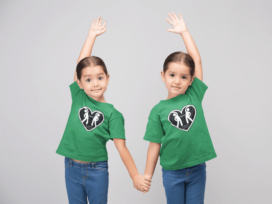 Two girls in green shirts holding hands, posing for the camera on a kids heavy cotton tee. Made with 100% US cotton, featuring twill tape shoulders and curl-resistant collar for durability and comfort.