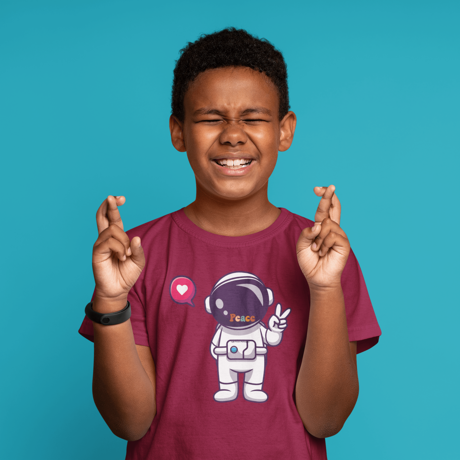 A toddler's Peace Astronaut T-shirt featuring a boy crossing fingers, astronaut cartoon, and heart bubble. Soft, durable 100% cotton, light fabric, tear-away label, classic fit.