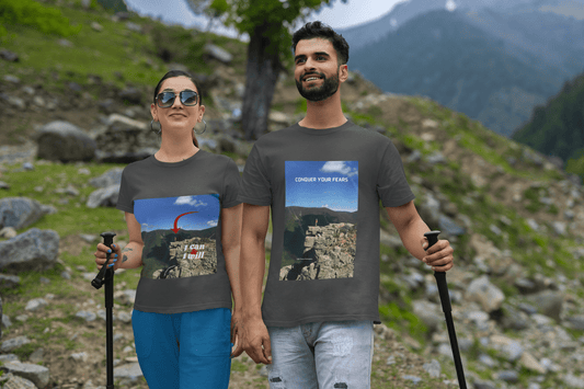 A man and woman in matching hiking t-shirts with mountain designs. Unisex heavy cotton tee for casual style, featuring smooth surface for vivid printing and durable tape on shoulders.