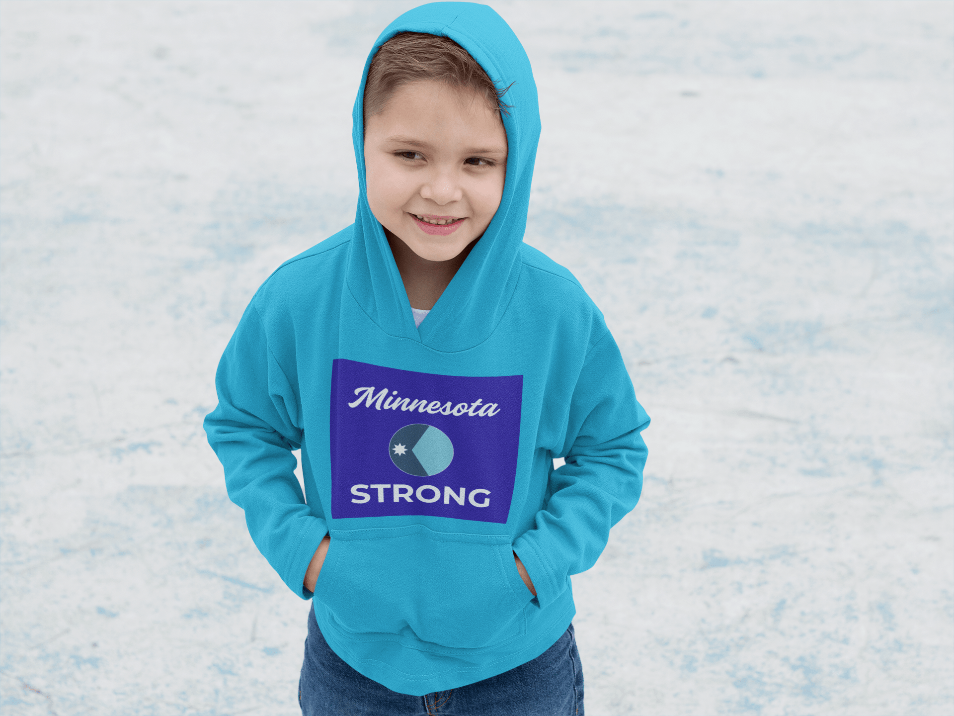 A child wearing the Minnesota Strong teal hoodie, featuring a cursive Minnesota and bold STRONG graphic, standing on an outdoor surface, smiling slightly.